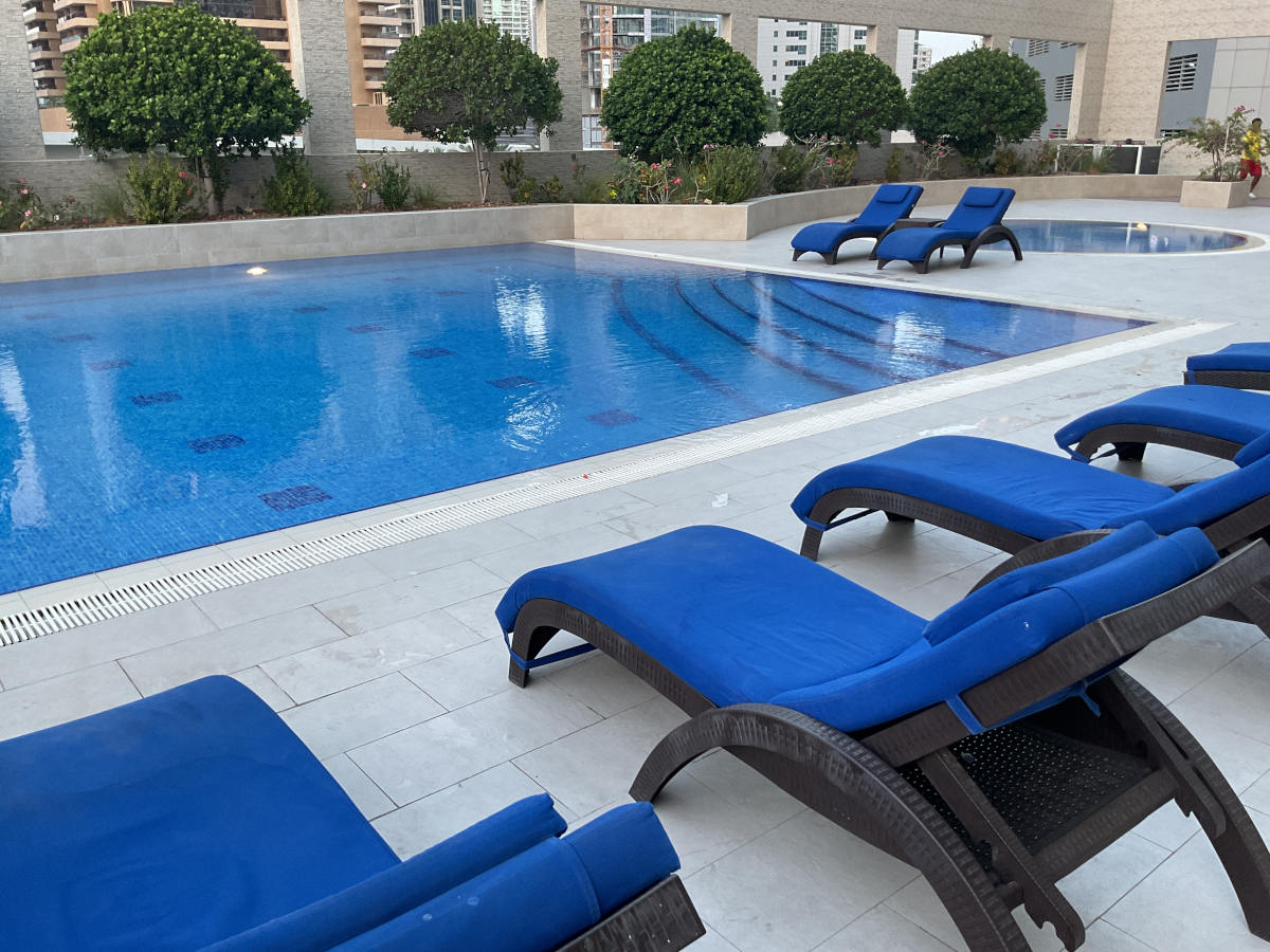 photo of swimming pool in Royal Oceanic Tower in Dubai with green leaves and a person in swimming pool